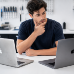 Older MacBook and modern laptop being compared by a repair technician